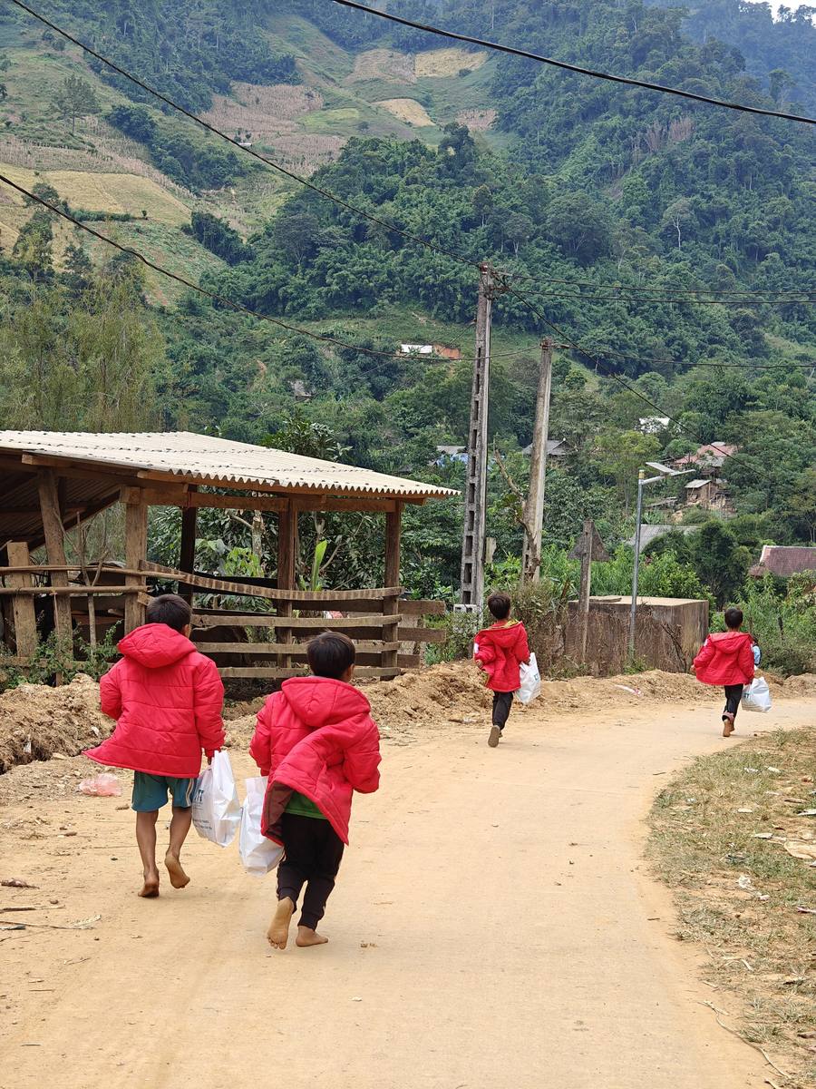 Children in red winter coats walking home along a mountain road